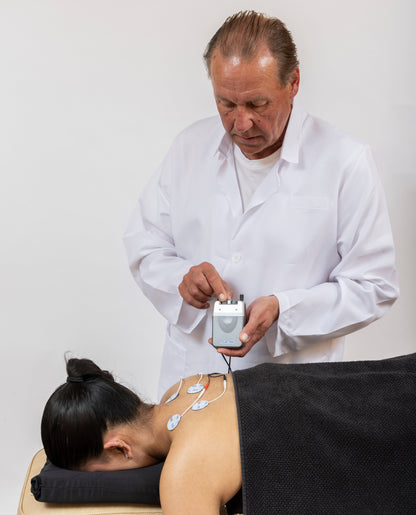 Man performing electroacupuncture on a person with electronic device against a white background